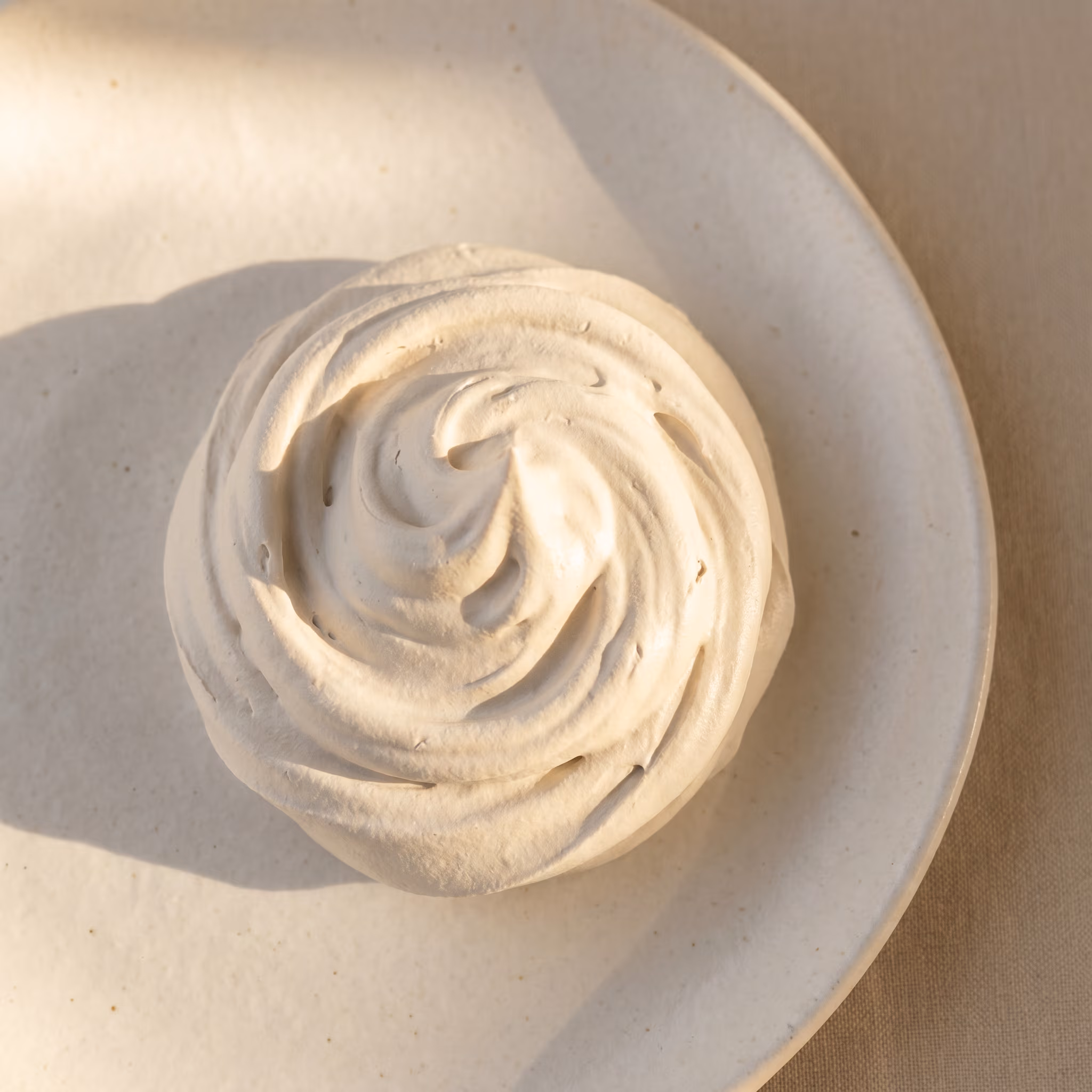 A swirl of cream — opaque, soft, lit from the right with a single highlight catching the peak.